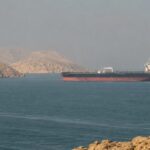 Oil tanker sailing through the Strait of Hormuz near a rocky coastline