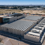 A large data center complex in the Gulf surrounded by desert infrastructure and power transmission lines