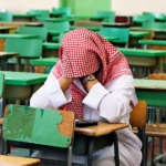 Saudi student sitting alone in a classroom during an exam