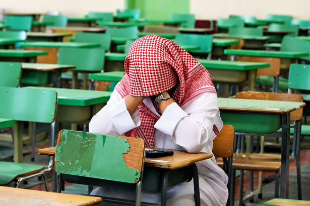 Saudi student sitting alone in a classroom during an exam