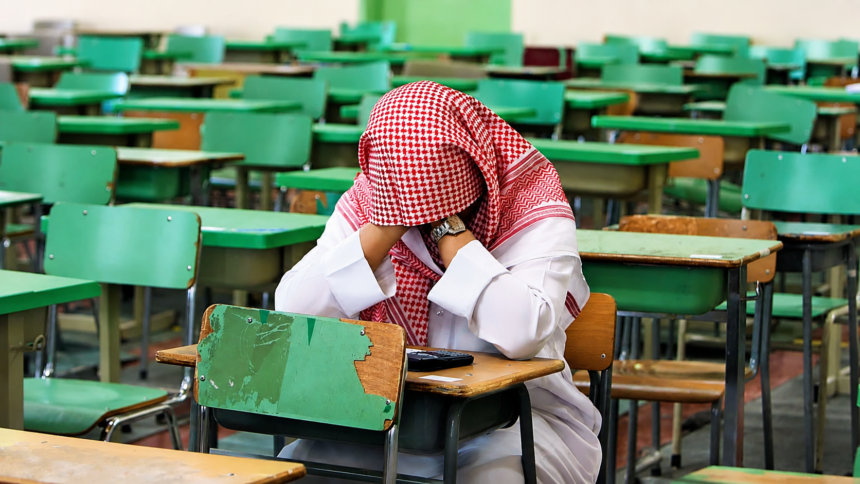 Saudi student sitting alone in a classroom during an exam