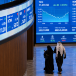Saudi investors walk past digital market screens at the Tadawul stock exchange in Riyadh