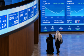 Saudi investors walk past digital market screens at the Tadawul stock exchange in Riyadh