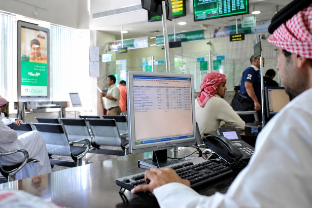 Saudi bank branch with customers and employees using digital banking systems