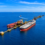 Two oil tankers moored at an offshore loading terminal in the Red Sea, with pipelines and marine infrastructure extending into the distance.