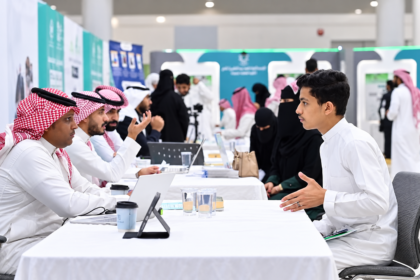 Young Saudi job seeker speaking with recruiters at a career fair