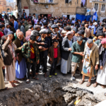 Residents gather around a large crater in a street in Sana’a, Yemen, following an attack