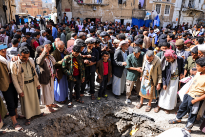 Residents gather around a large crater in a street in Sana’a, Yemen, following an attack